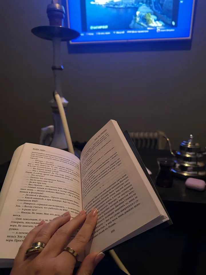 Гость читает книгу за столиком в приглушённом свете CloudHut